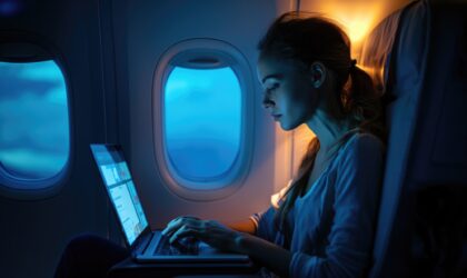 Marketing de oportunidade: mulher sentada em poltrona ao lado da janela do avião, observando o notebook.